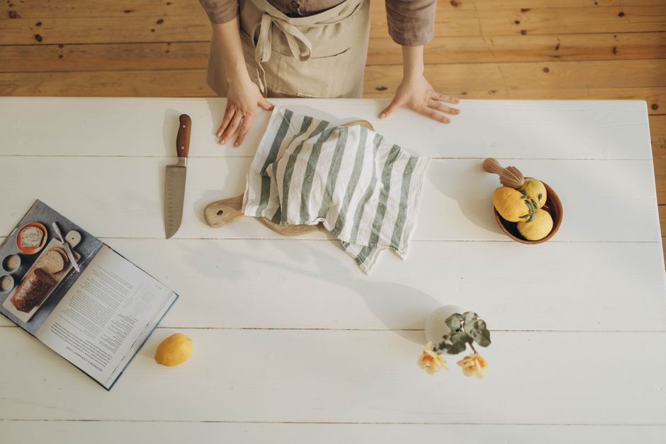 Overhead view of a woman in a kitchen preparing a meal with lemons and cookbook.